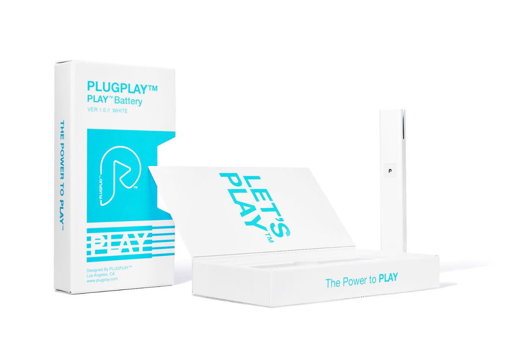 A white PLAY battery with blue and black text, alongside its packaging which has similar color scheme. The packaging also features the text 'The Power is PLAY'.